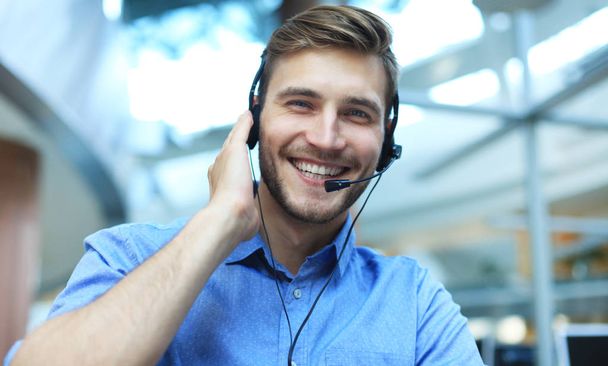 Smiling friendly handsome young male call centre operator. - 写真・画像