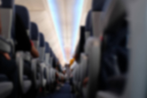 passenger sit on seat in airplane.  aisle in aeroplane interior. blurry defocused background - Photo, Image