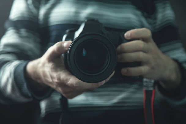 Professional photographer holding a DSLR camera. - Zdjęcie, obraz