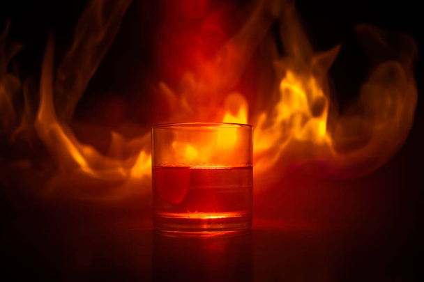 Виски в огне концепции. Стакан виски и лед на деревянной поверхности с цветным светом и туманом на заднем плане. Закрывай. Селективный фокус
 - Фото, изображение