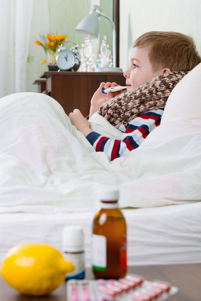 Sick little boy lying in bed with thermometer - Фото, зображення