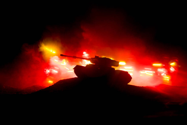 Concepto de guerra. Silueta de tanque blindado Debajo del cielo de fuego de niebla por la noche. Escena de ataque. Decoración de juguete. Enfoque selectivo
 - Foto, imagen