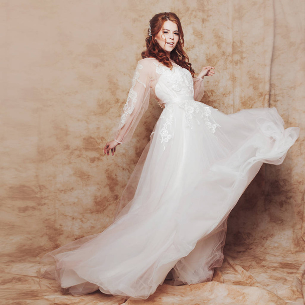 Beautiful and romantic bride in wedding dress with light and fluffy skirt. Young redheaded woman in wedding dress - Фото, зображення