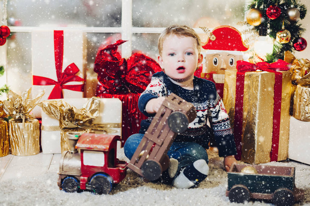Little blonde boy playing with Christmas presents and boxes. - Foto, Bild