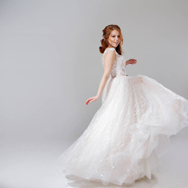 Lovely young woman bride in lavish wedding dress. Light background. - 写真・画像