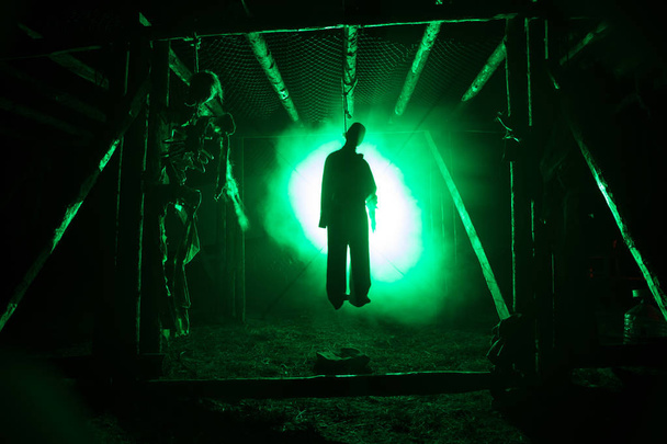 夜の霧に足場に吊された男と背景にトーンの光のホラー ビュー シルエット。実行 (または自殺) の装飾。ホラー ・ ハロウィン ・ コンセプト. - 写真・画像