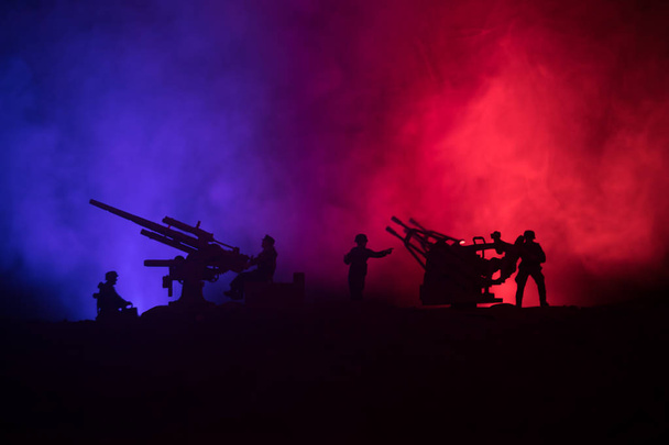 Un canon anti-aérien et des silhouettes militaires combattant sur fond de brouillard de guerre, des silhouettes de soldats de la guerre mondiale sous un ciel nuageux la nuit
 - Photo, image