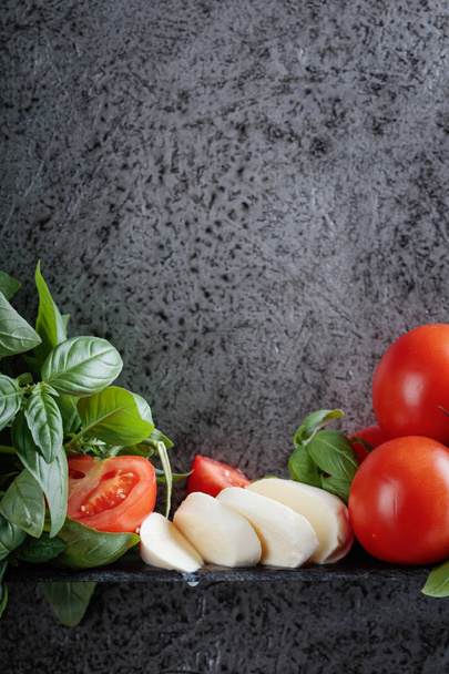 Mozzarella with basil and tomatoes on a background of old grey wall. Copy space for your text. - Фото, зображення