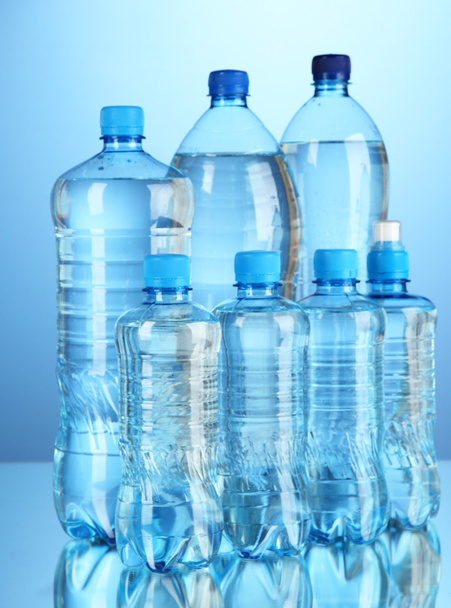 Different water bottles on blue background - Фото, изображение