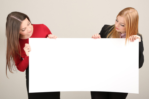 Két üzleti nők, a szürke háttér üres űrlap - Fotó, kép