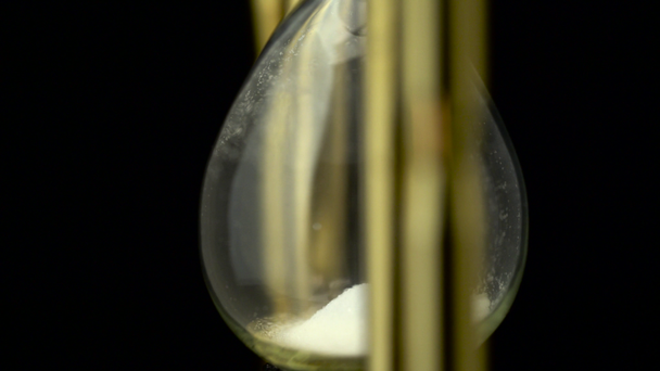 Sand in the hourglass with a black background they rotate. Close up - Filmmaterial, Video