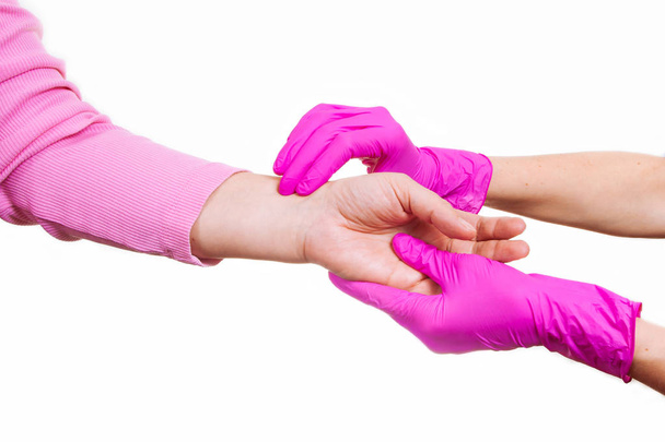 Les mains féminines d'une infirmière ou d'un médecin en gants médicaux roses tiennent la main d'une vieille femme. Concept de soins et de soutien en hospice
. - Photo, image