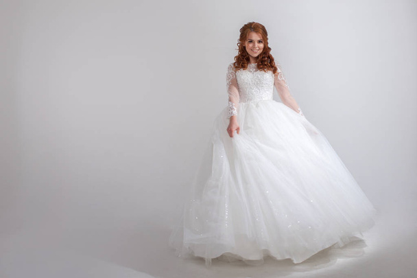 Lovely young woman bride in a lavish wedding dress. Light background. - Фото, зображення