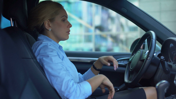 Unhappy woman sitting in car, exhausted after hard working day, overworked - Filmagem, Vídeo