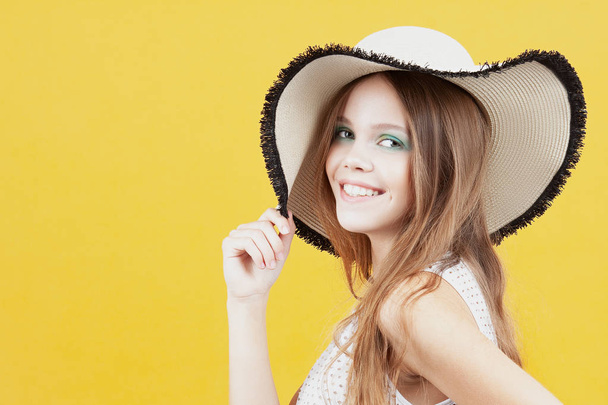Hasır şapkalı genç kız sarı zemin üzerine gülümsüyor. Duygu ve hareketleri - Fotoğraf, Görsel
