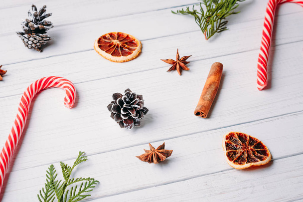 malli joulukarkkeja, mänty käpyjä ja kuivattuja appelsiineja valkoisella puupohjalla. Joulukoristeet
 - Valokuva, kuva