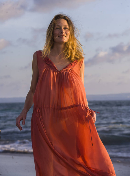junge glückliche schöne und glamouröse blonde Frau posiert wie am Strand in stilvollem Kleid lächelnd fröhliches Gefühl frisch und frei am Meer in Urlaub Reisen und Beauty-Modekonzept - Foto, Bild