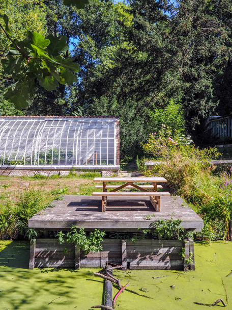 Small picnic area next to an old greenhouse and the river in the center of the Roosendael Abbey public park in Walem, near Mechelen, Belgium - Photo, Image