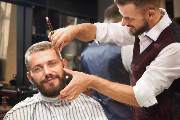 Front view of satisfied male in barber shop getting haircut - 写真・画像