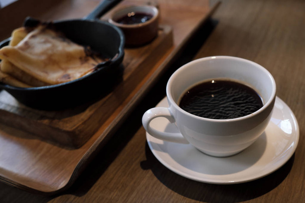 Uma xícara de café e panquecas em uma panela de ferro fundido
. - Foto, Imagem
