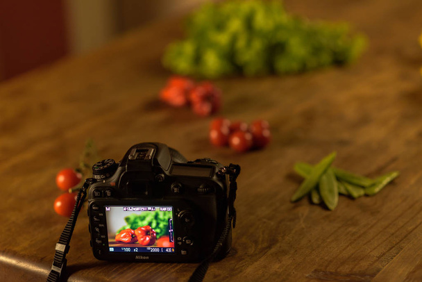 andorra la vella, andorra: camara d7100 nikon in photo session mit kirschtomaten, grünen bohnen, salat und paprika. - Foto, Bild
