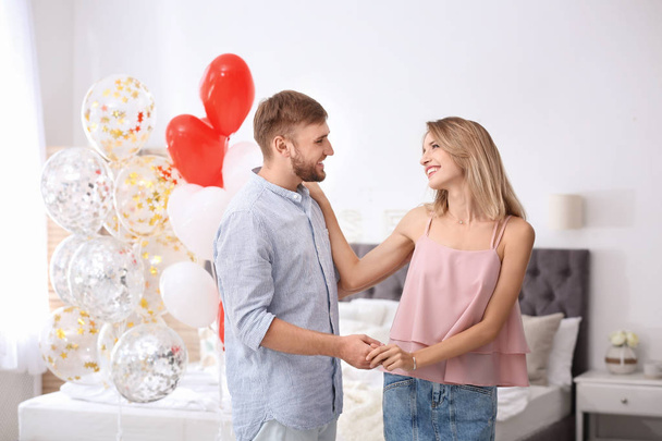 Young couple with air balloons in bedroom. Celebration of Saint Valentine's Day - Фото, зображення