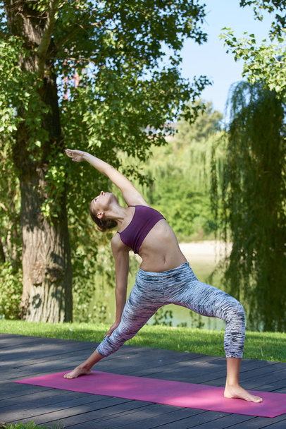 Teljes hossza lövés csinálás jóga szabadtéri sportos fiatal nő.  - Fotó, kép