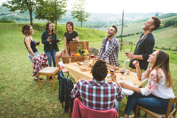 Group of young happy friends having pic-nic outdoors - People having fun and celebrating while grilling ata barbacue party in a countryside - Фото, изображение