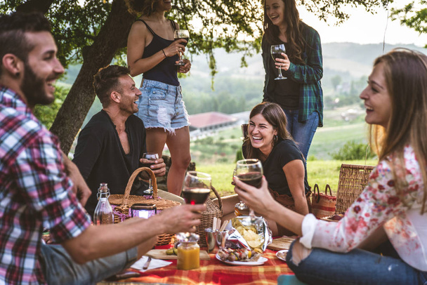Group of young happy friends having pic-nic outdoors - People having fun and celebrating while grilling ata barbacue party in a countryside - Foto, immagini