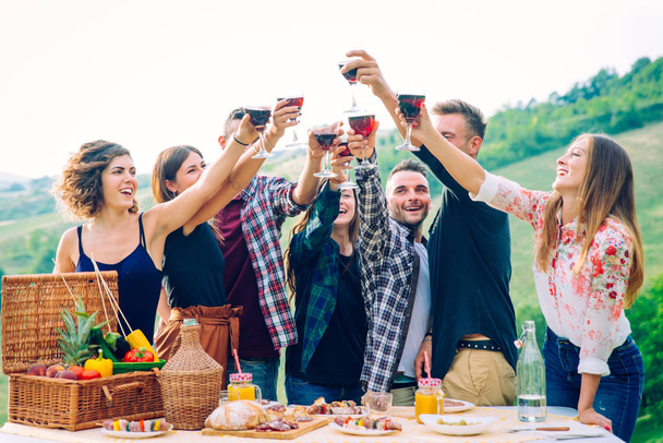 Group of young happy friends having pic-nic outdoors - People having fun and celebrating while grilling ata barbacue party in a countryside - 写真・画像