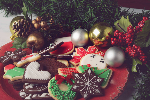 Nahaufnahme von bunten Weihnachtsplätzchen mit festlicher Dekoration auf einem Holztisch. Weihnachtsferien-Konzept. - Foto, Bild