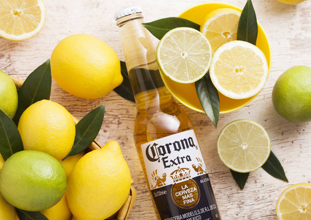 LONDON, UK - APRIL 27, 2018: Glass Bottle of Corona Extra Beer on wooden background with fresh lemons.Corona, produced by Grupo Modelo. - Foto, Bild