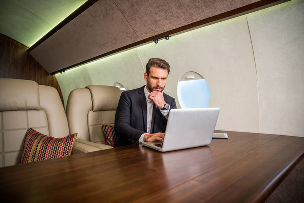 Businessman working while travelling on private jet - Portrait of business people taking a first class flight for work, concepts about business and mobility - Φωτογραφία, εικόνα