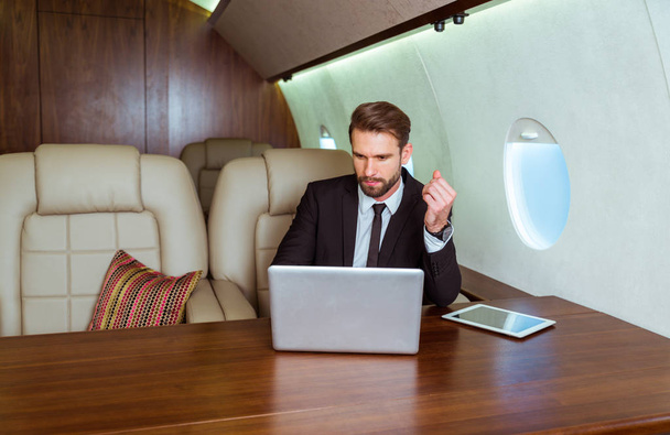 Businessman working while travelling on private jet - Portrait of business people taking a first class flight for work, concepts about business and mobility - Fotoğraf, Görsel