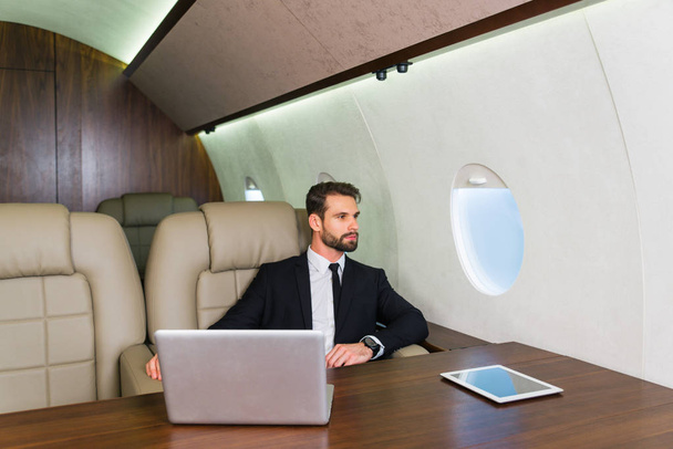 Businessman working while travelling on private jet - Portrait of business people taking a first class flight for work, concepts about business and mobility - Фото, изображение