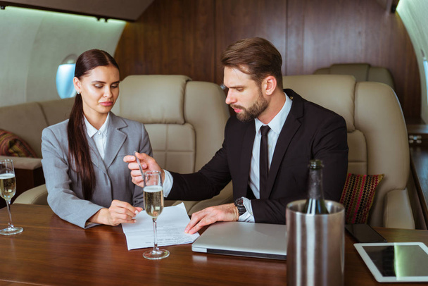 Businessman and woman working while travelling on private jet - Portrait of business people taking a first class flight for work, concepts about business and mobility - Фото, зображення