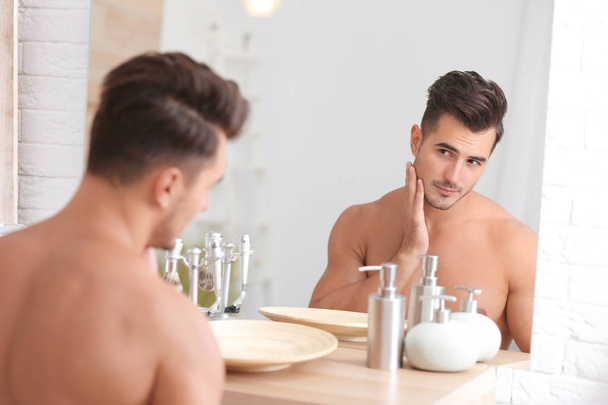 Young man with stubble ready for shaving near mirror in bathroom - Zdjęcie, obraz