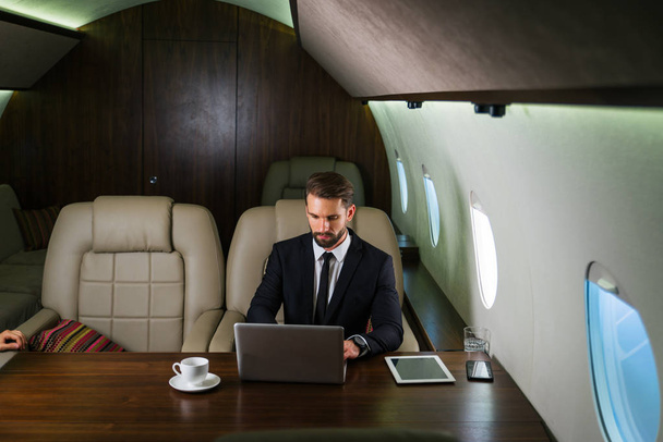 Businessman working while travelling on private jet - Portrait of business people taking a first class flight for work, concepts about business and mobility - Foto, imagen