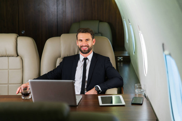Businessman working while travelling on private jet - Portrait of business people taking a first class flight for work, concepts about business and mobility - Photo, Image