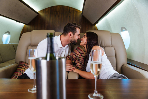 Happy couple travelling on a luxury private jet - Young adults travel on a first class flight, concepts about travel and lifestyle - Foto, imagen