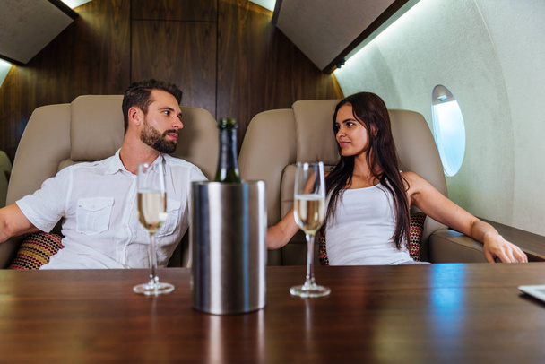 Happy couple travelling on a luxury private jet - Young adults travel on a first class flight, concepts about travel and lifestyle - Zdjęcie, obraz