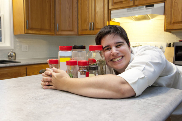 Osoba w strój kucharza przytula kilka przypraw w pojemnikach w kuchni - Zdjęcie, obraz