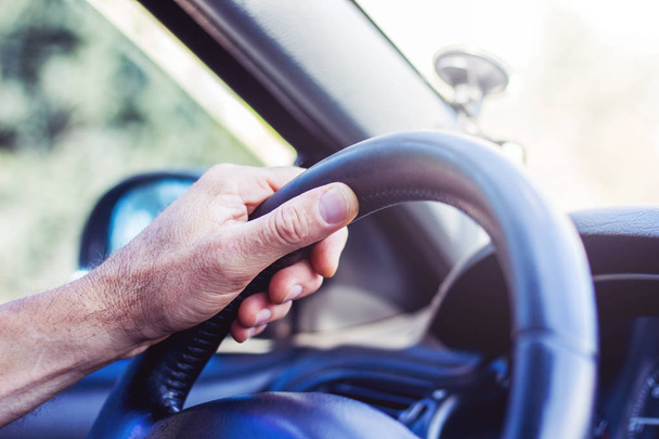 Του ανθρώπου χέρι στο τιμόνι ενός αυτοκινήτου. Οδήγηση στο δρόμο - Φωτογραφία, εικόνα