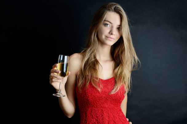 Young woman wearing red skirt for party. Girl holding glass of white wine or champagne, enjoying her drink. - Zdjęcie, obraz