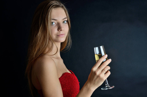 Nuori nainen, jolla on punainen hame juhlissa. Tyttö tilalla lasi valkoviiniä tai samppanjaa, nauttia hänen juoda
. - Valokuva, kuva