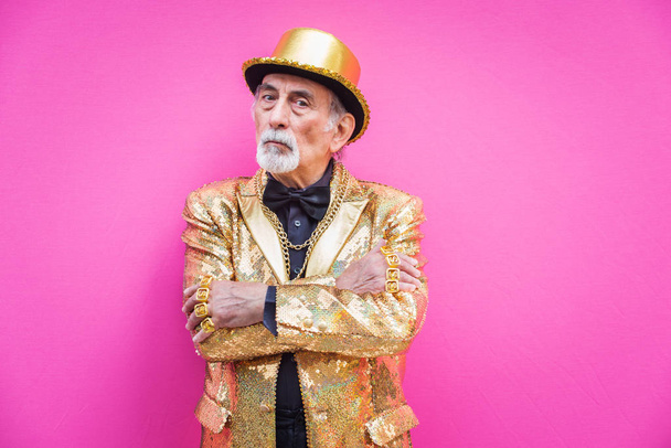 Funny and extravagant senior man posing on colored background - Youthful old man in the sixties having fun and partying - Фото, зображення