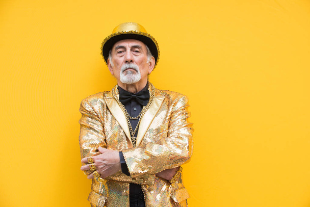 Funny and extravagant senior man posing on colored background - Youthful old man in the sixties having fun and partying - Foto, Imagem