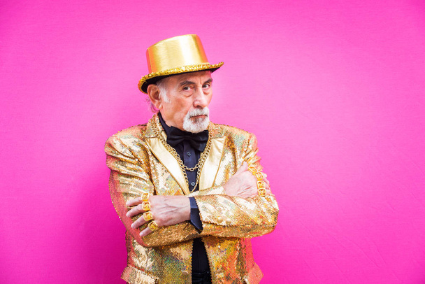 Funny and extravagant senior man posing on colored background - Youthful old man in the sixties having fun and partying - Fotó, kép