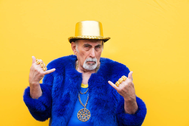 Funny and extravagant senior man posing on colored background - Youthful old man in the sixties having fun and partying - Foto, immagini