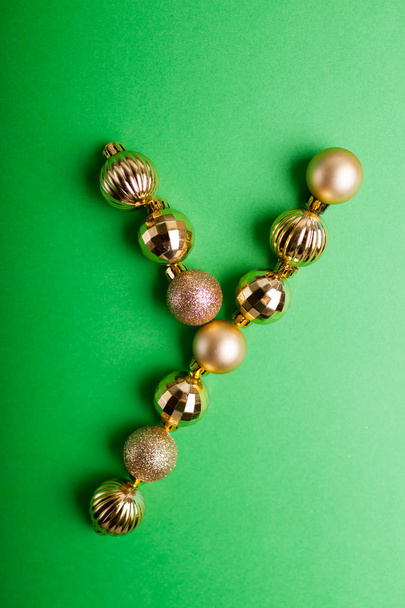 Letra Y hecha de juguetes de Navidad sobre fondo verde. ABC hecho de bolas de oro
 - Foto, imagen